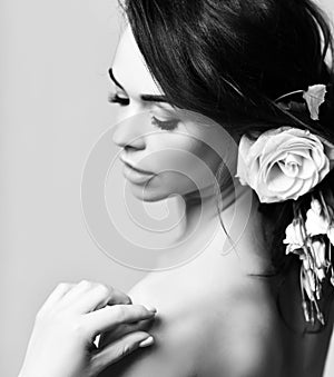 Sensual curly hair beautiful mature woman mysteriously smiles with rose flowers in hair. Black and white