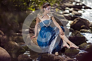 Sensual Dreaming Mermaid of Sea in Artistic Caucasian Blond Woman With Strasses on Face Sitting in Blue Wet Dress on Rocky Shore
