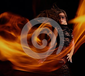 Sensual girl in black dress dancing with flame photo