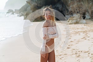 sensual girl in nude swimwear posing on deserted beach