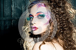 Sensual girl with paited face. Art make up of sexy woman with bright makeup and fashion feather eyelashes.