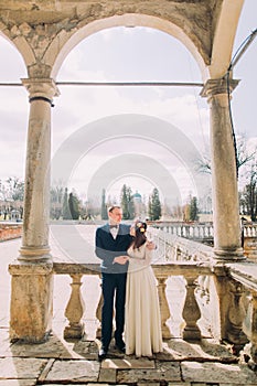 Sensual husband and wife hugging under archway in antique ruined palace