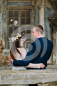 Sensual husband and wife hugging under archway in antique ruined palace. Back view