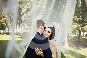 Sensual kiss of bride and groom under veil