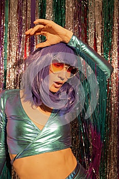 Sensual Lady 80s dancing in stylish holographic party look. Tinsel installation. New year`s clubbing concept. Merry christmas.