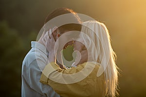 Sensual lovers hugging and kissing at sunset. Young couple in love spends time together. Man embracing and going to kiss