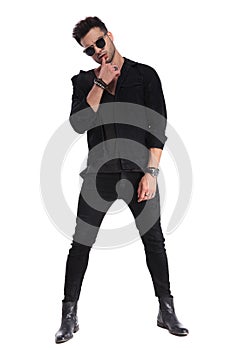 Sensual macho man in black clothes standing with parted feet photo