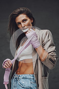 Sensual middleaged female athlete poses in dark background pulling bandage