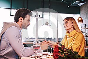Sensual moments. Young man holding hands of his girlfriend in restaurant