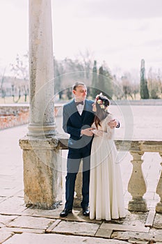 Sensual newlywed husband and wife hugging under archway in antique ruined palace