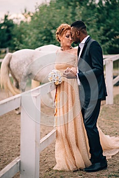 Sensual newlyweds stand on ranch surrounded by horses
