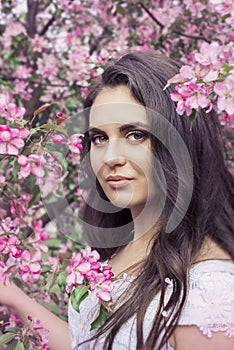 Sensual portrait of a spring woman, beautiful face, close up on blue eyes, female enjoying cherry blossom