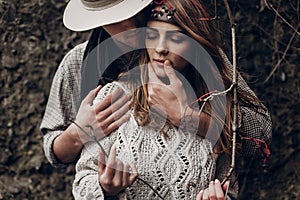 Sensual romantic man in cowboy hat hugging a beautiful gypsy brunette woman from behind, while she is holding a berry tree branch