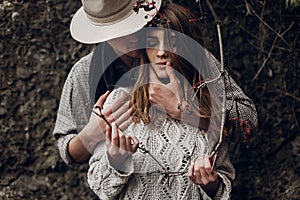 Sensual romantic man in cowboy hat hugging a beautiful gypsy brunette woman from behind, while she is holding a berry tree branch
