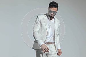 Sensual smart casual man in white suit looking down and posing