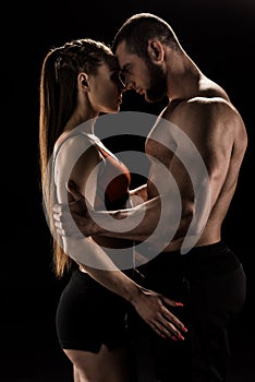Sensual sporty couple embracing isolated on black photo