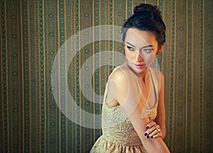Sensual style. a beautiful young woman dressed elegantly in a wallpapered room.
