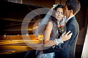 Sensual wedding portrait. The handsome groom is tenderly kissing his beautiful bride in the forehead at the background