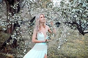 Sensual woman, blonde fashion model in flower blossom garden, spring. Soft focus