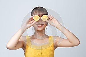 sensual woman covering eyes with half of lemon isolated on white