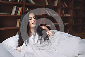 Sensual woman with dark hair lying on a bed