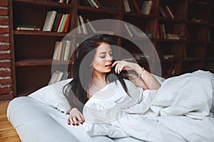 Sensual woman with dark hair lying on a bed