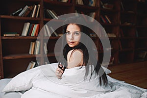 Sensual woman with dark hair sitting on a bed