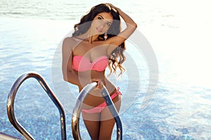 Sensual woman in elegant bikini posing beside swimming pool