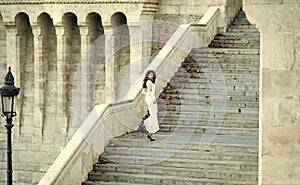 Sensual woman. Fashion bride in white wedding dress on staircase. Fashion model with long hair on stair steps