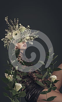 A sensual woman with floral headdress poses amidst lush leaves and blooms in an artistic botanical portrait