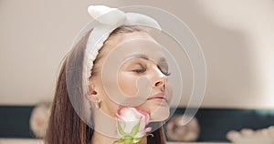 Sensual woman in headband smelling rose bud.