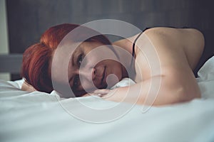Sensual woman in her bed at dawn, between the sheets of her bedroom at home
