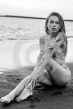 Sensual woman posing on the beach, looking at the camera. Portrait of beautiful young woman. Sexy tanned girl with wet hair