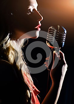 Sensual woman with red lips sings into a microphone. The singer records the song in a professional studio