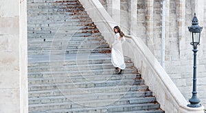 Sensual woman on staircase. Woman bride in white wedding dress, fashion. Girl with glamour look. Fashion model with long