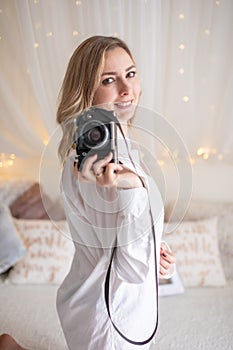 Sensual woman takes a photo of an old camera in bed