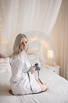 Sensual woman takes a photo of an old camera in bed