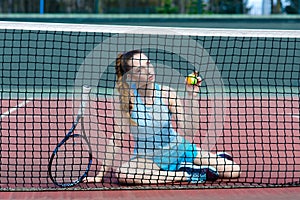 Sensual woman with tennis racket at net on lawn. Activity, energy, power. Sport, training, workout. Wellness, health