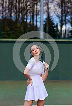 Sensual woman with tennis racket at net on lawn. Activity, energy, power. Sport, training, workout. Wellness, health