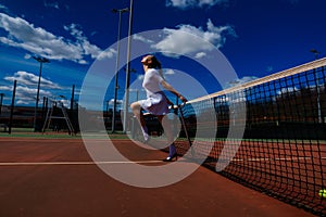 Sensual woman with tennis racket at net on lawn. Activity, energy, power. Sport, training, workout. Wellness, health
