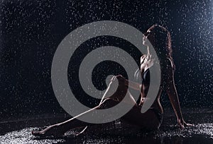 Sensual woman under water drops. Dark background