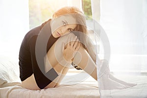 Sensual woman wearing black pullover is sitting in bed on a sunny day