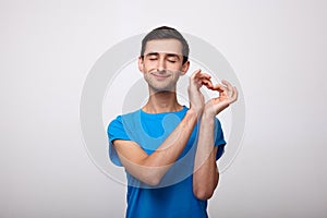 Sensual young man with his eyes closed shows his heart with his hands