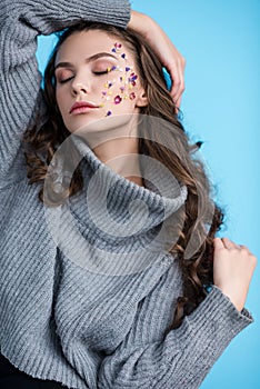 sensual young woman with closed eyes and flowers on face posing