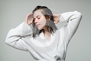 Sensual young woman portrait in bathrobe. Morning female model relaxing with wet hair. Hair care and beauty. Morning