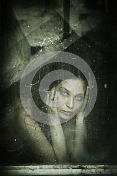 Sensual young woman portrait behind old dirty window