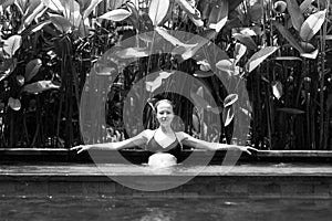 Sensual young woman relaxing in outdoor spa infinity swimming pool surrounded with lush tropical greenery of Ubud, Bali