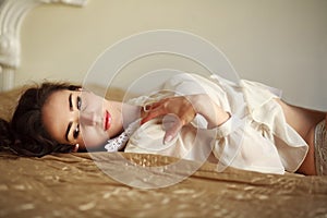 Sensual young woman thoughtfully lying on the bed at home