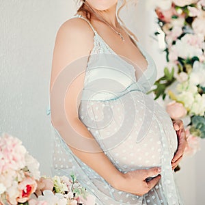 Sensuality pregnant in lingerie dress embrasing stomach and smiling.