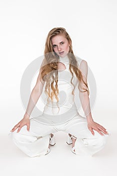 Sensuality young blonde woman well dressed white jumpsuit and slingbacks sitting squatting position